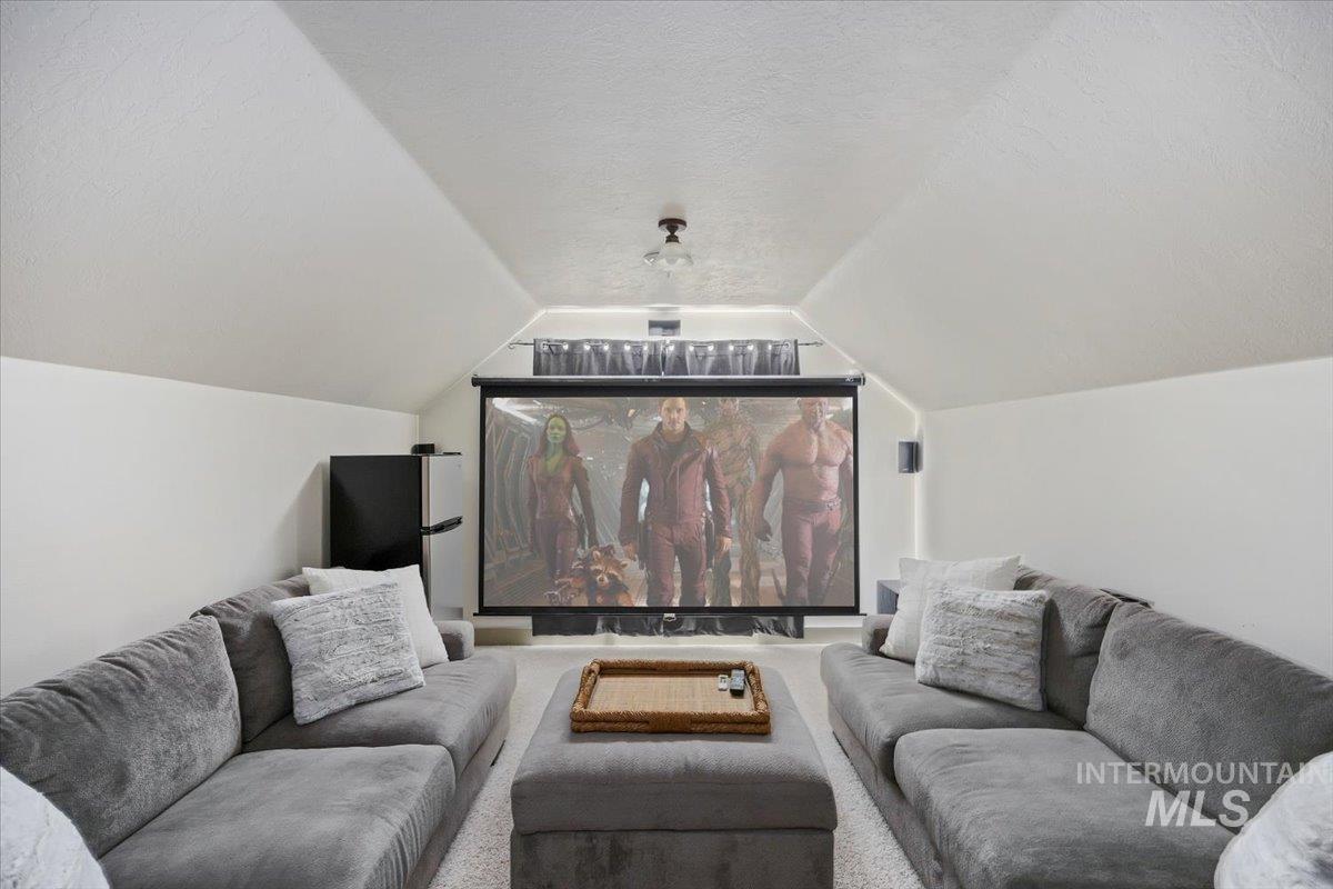 Home theater room with vaulted ceiling and a textured ceiling