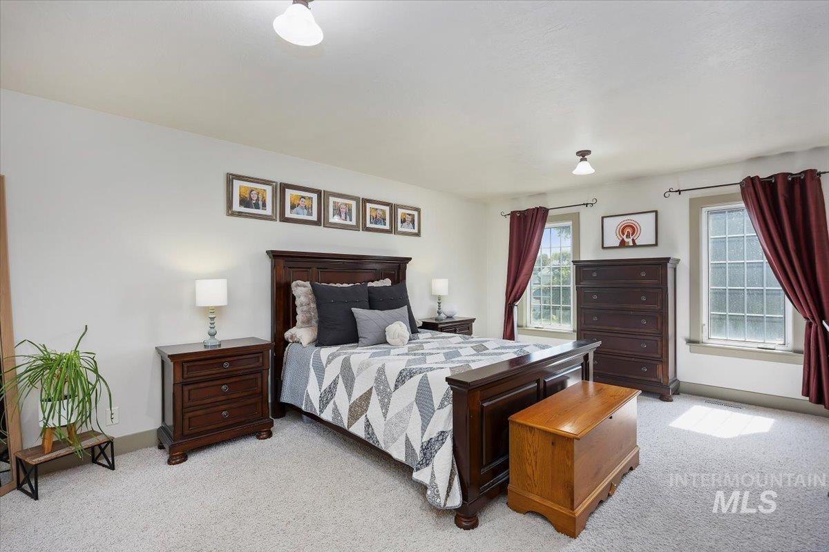 Bedroom featuring light carpet and multiple windows
