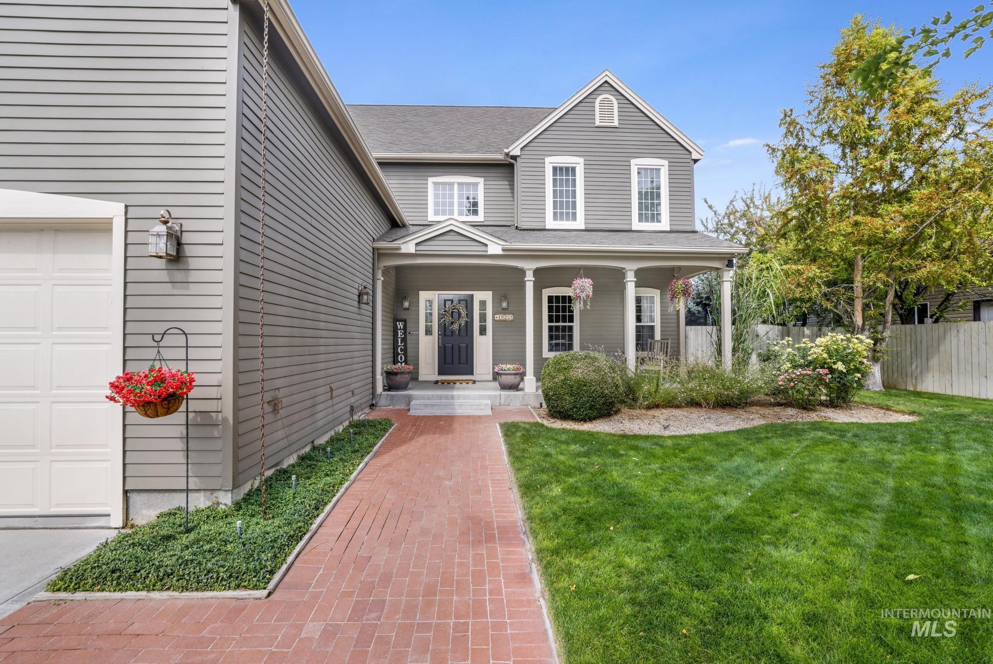 Traditional home featuring covered porch, a shingled roof, and a garage