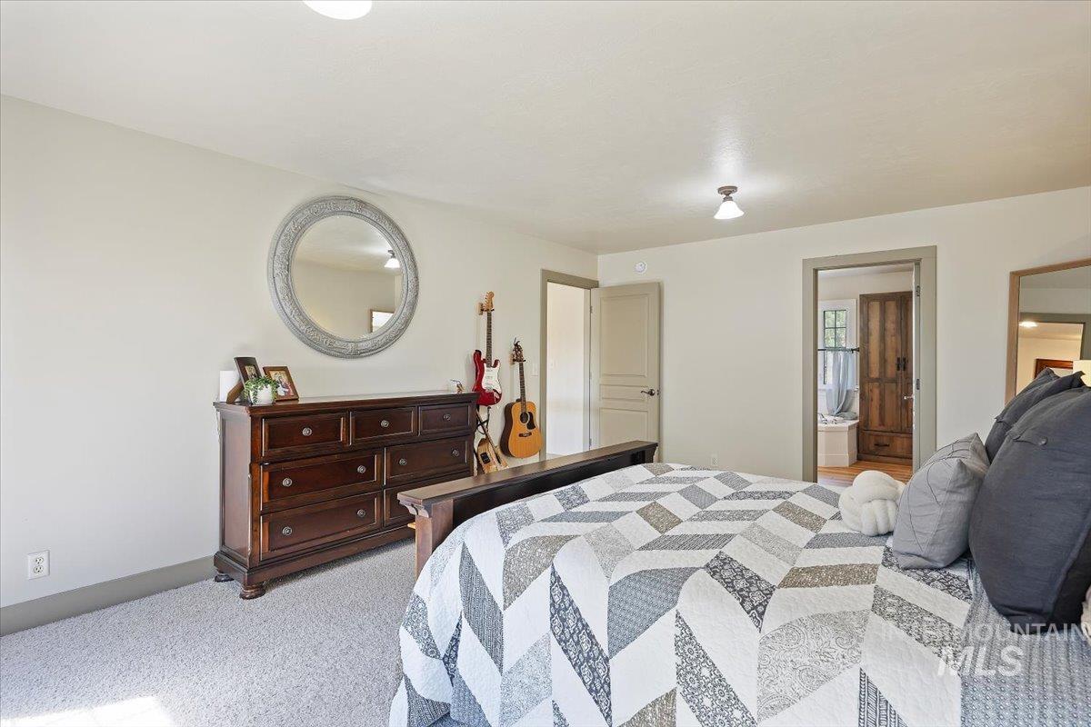 Bedroom featuring light colored carpet and ensuite bathroom