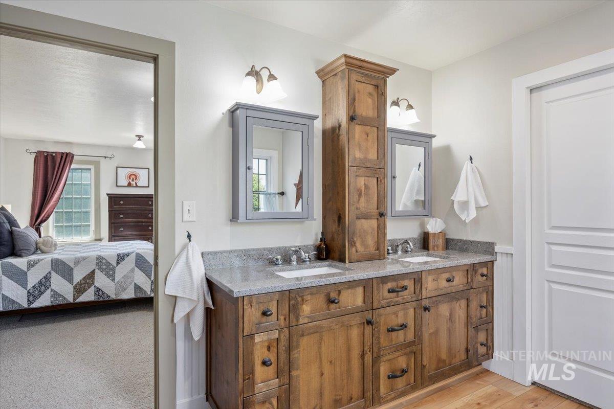 Ensuite bathroom with double vanity and light wood finished floors