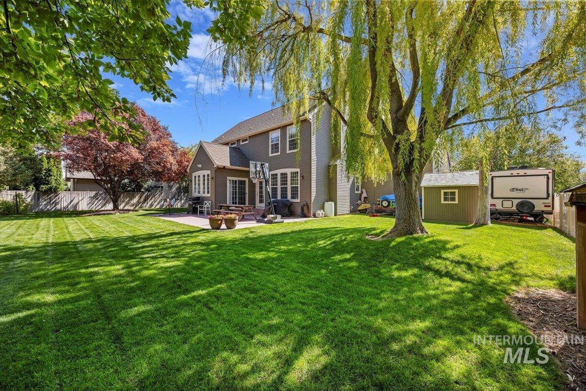 Back of property with a fenced backyard, a patio area, and a storage shed