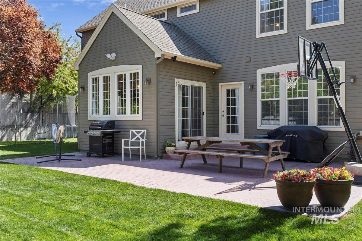 Rear view of house with a patio, a lawn, and a shingled roof