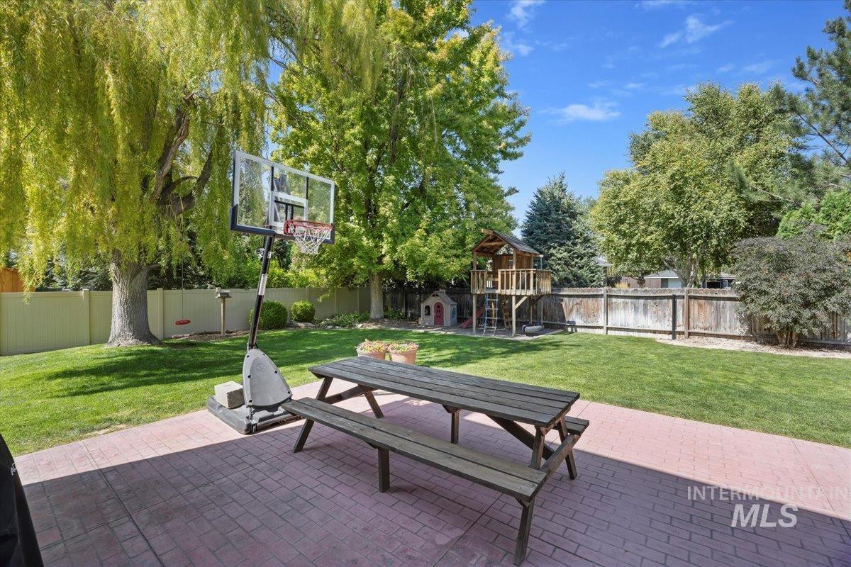 Fenced backyard featuring a playground, a patio, and outdoor dining area