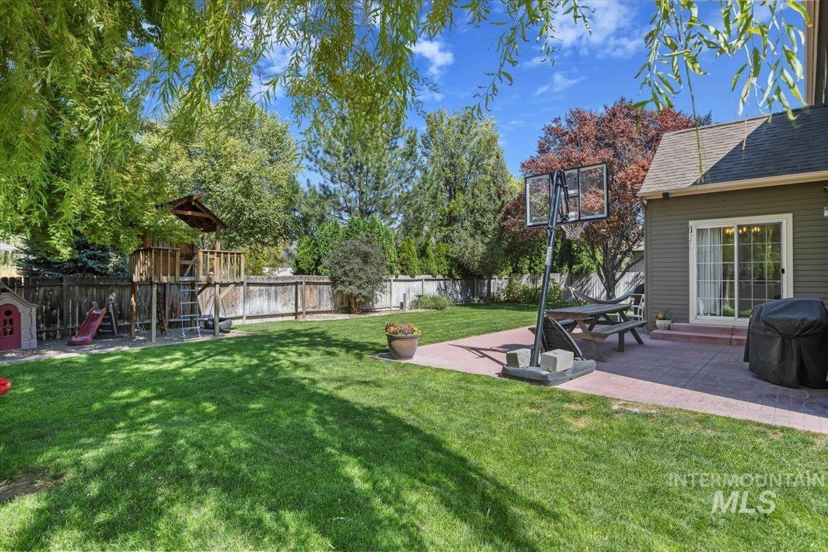Fenced backyard with a playground and a patio area