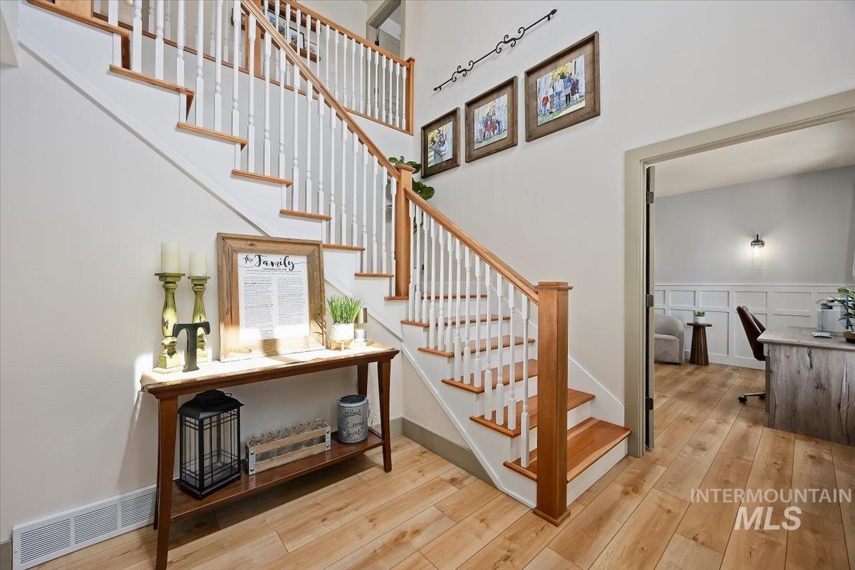 Staircase with wood-type flooring, a wainscoted wall, and a decorative wall