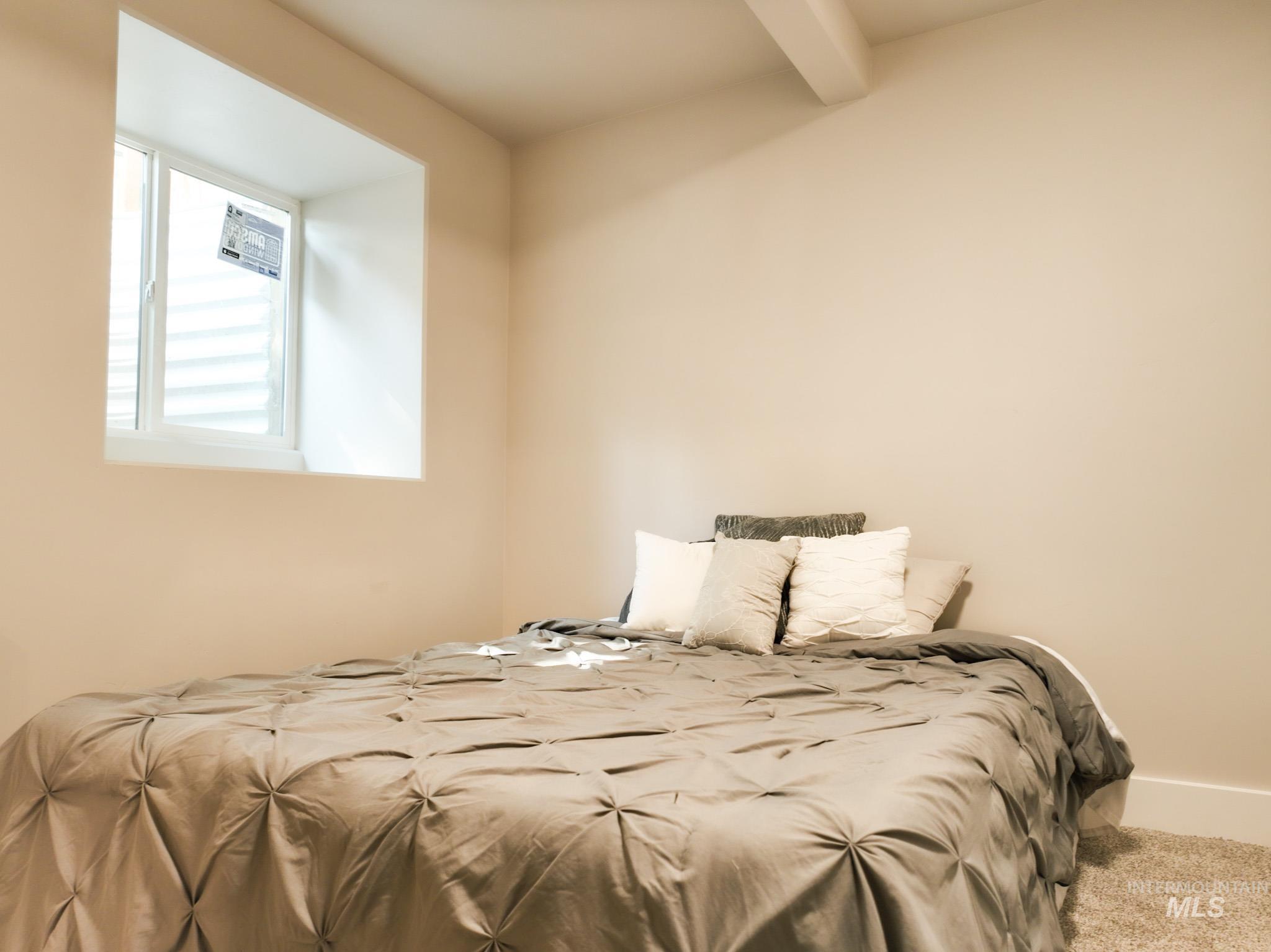 Carpeted bedroom with beam ceiling and baseboards