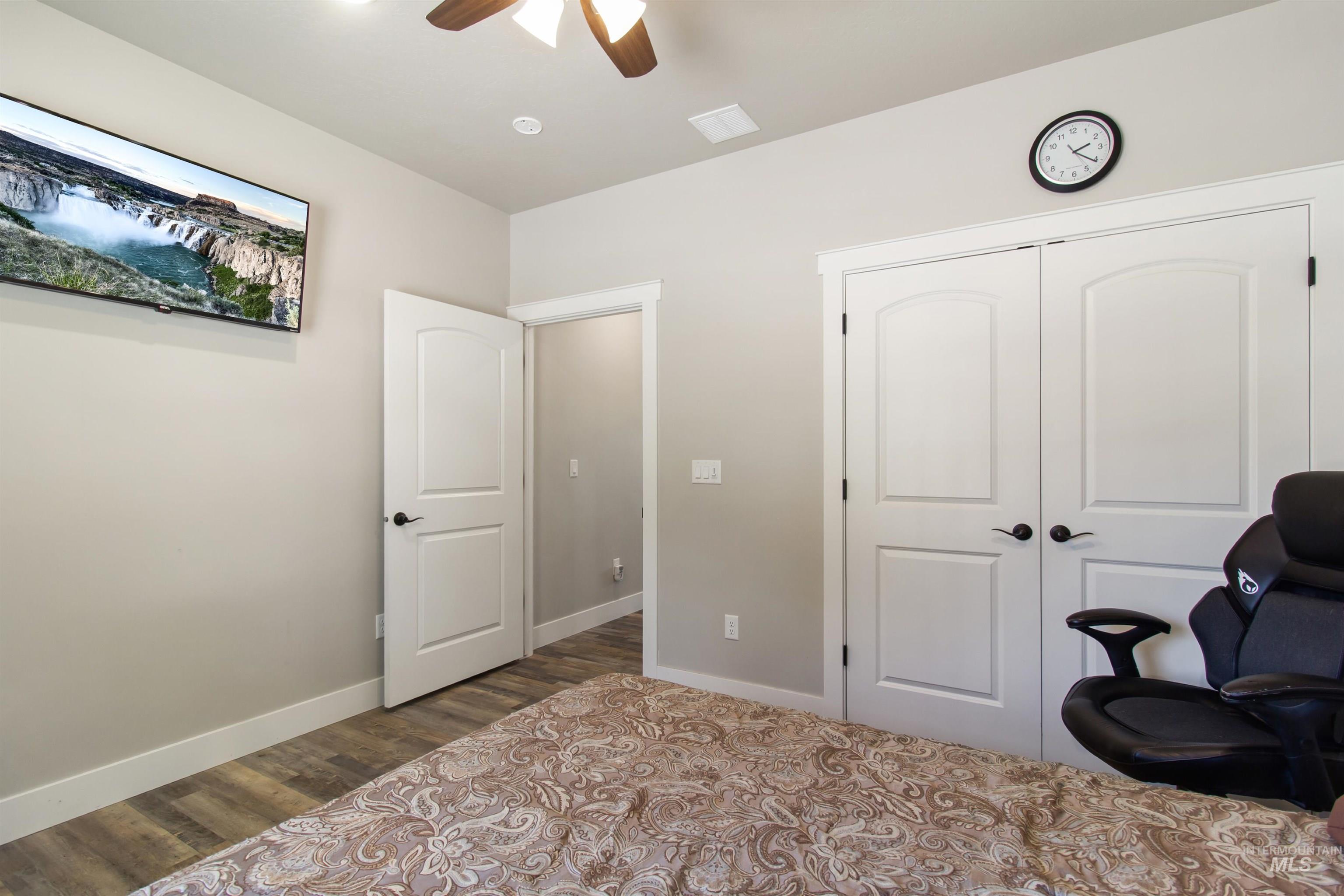 Bedroom with dark wood-style flooring, a closet, and a ceiling fan
