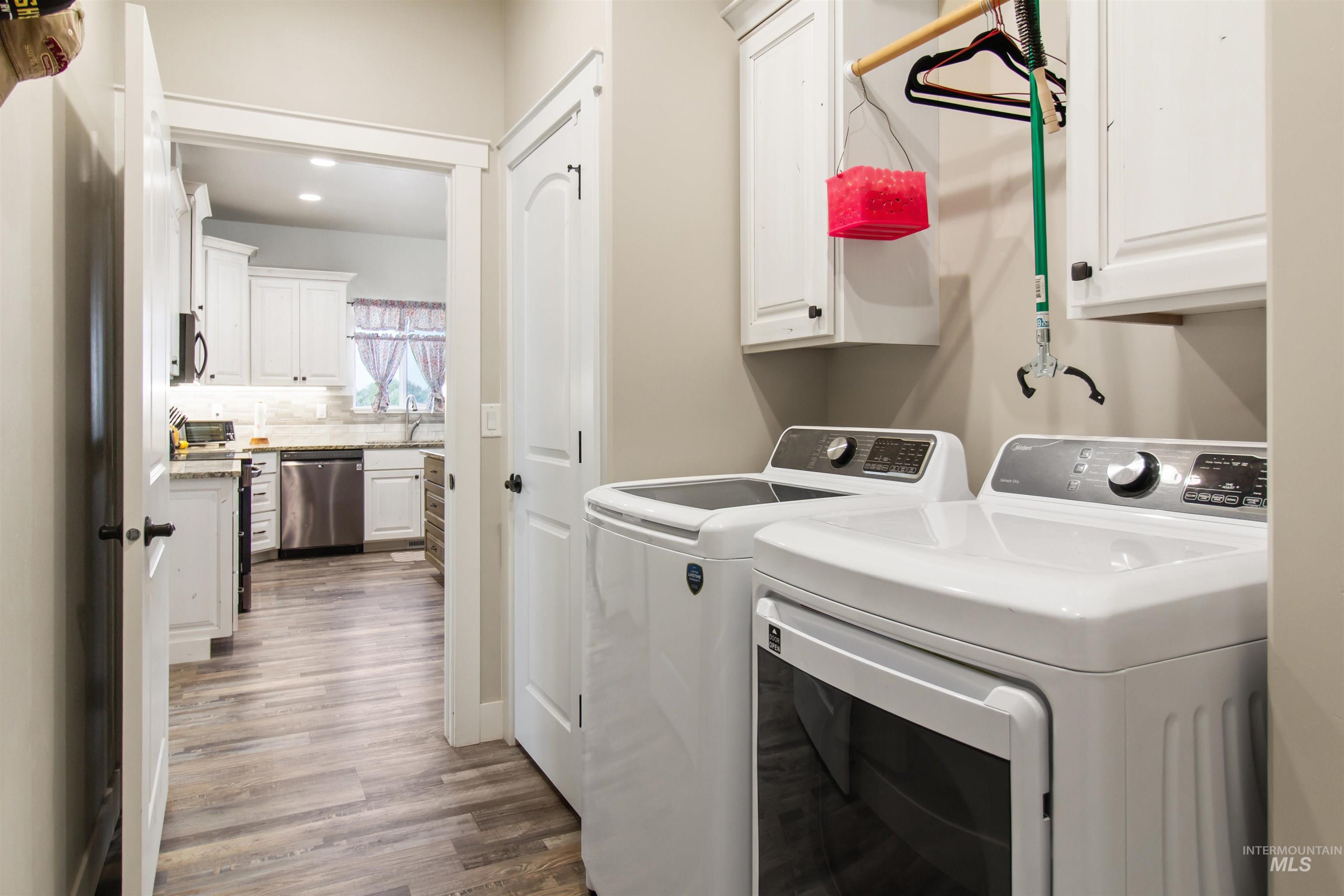 Laundry room featuring washing machine and dryer, wood finished floors, cabinet space, and recessed lighting
