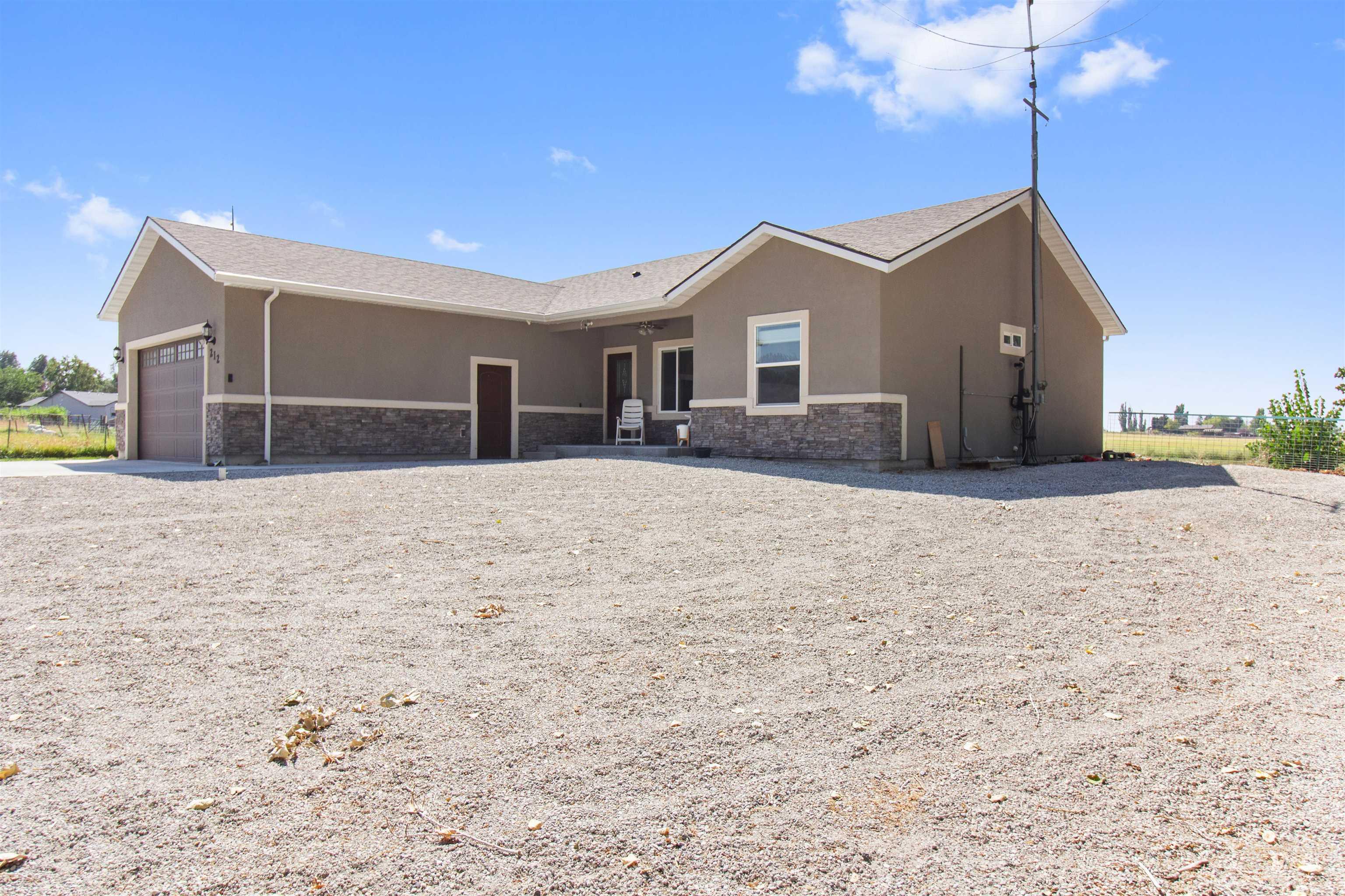 Rear view of property with stone siding, stucco siding, a garage, and driveway
