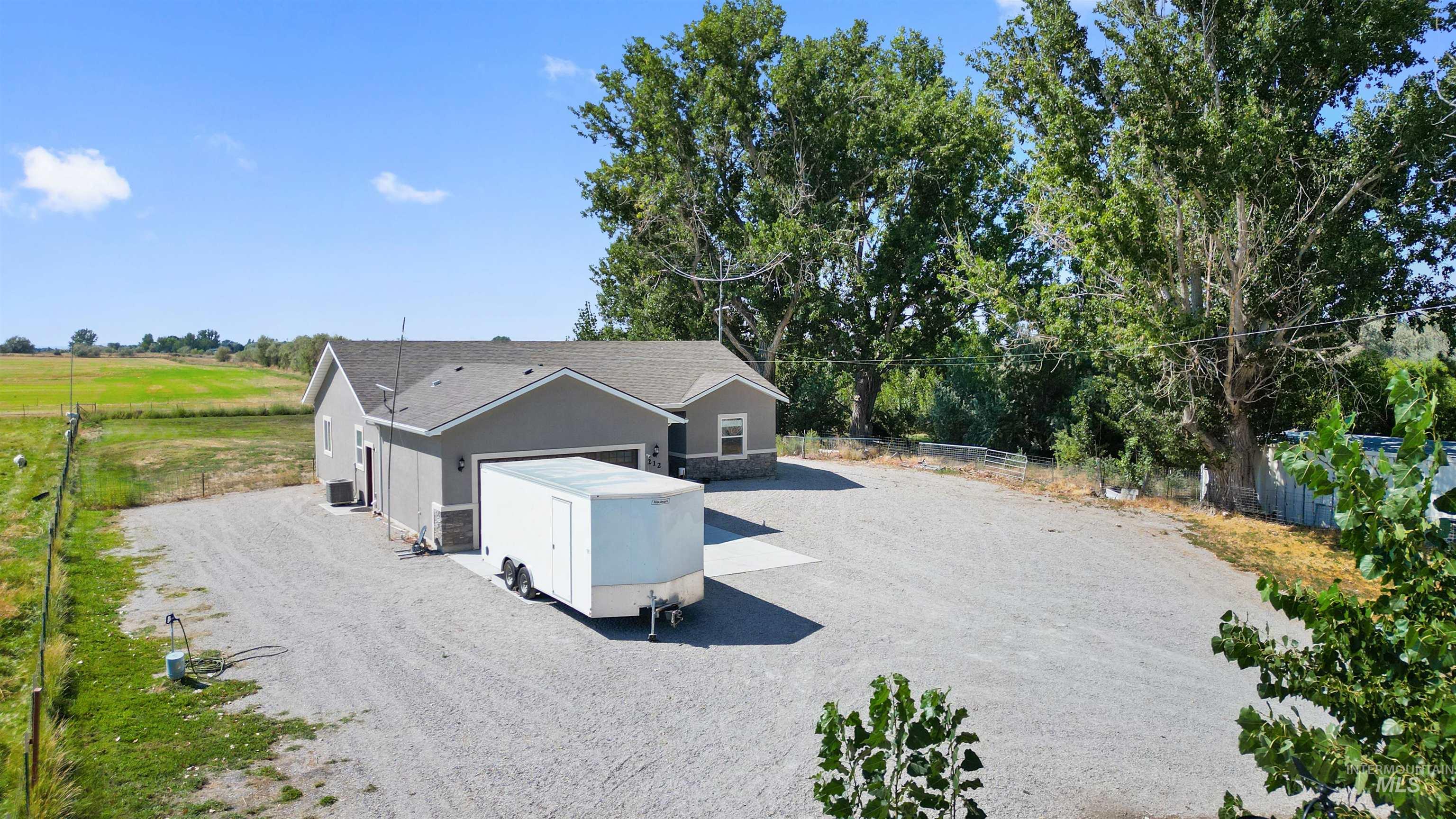 Back of property with driveway, stucco siding, a garage, and stone siding