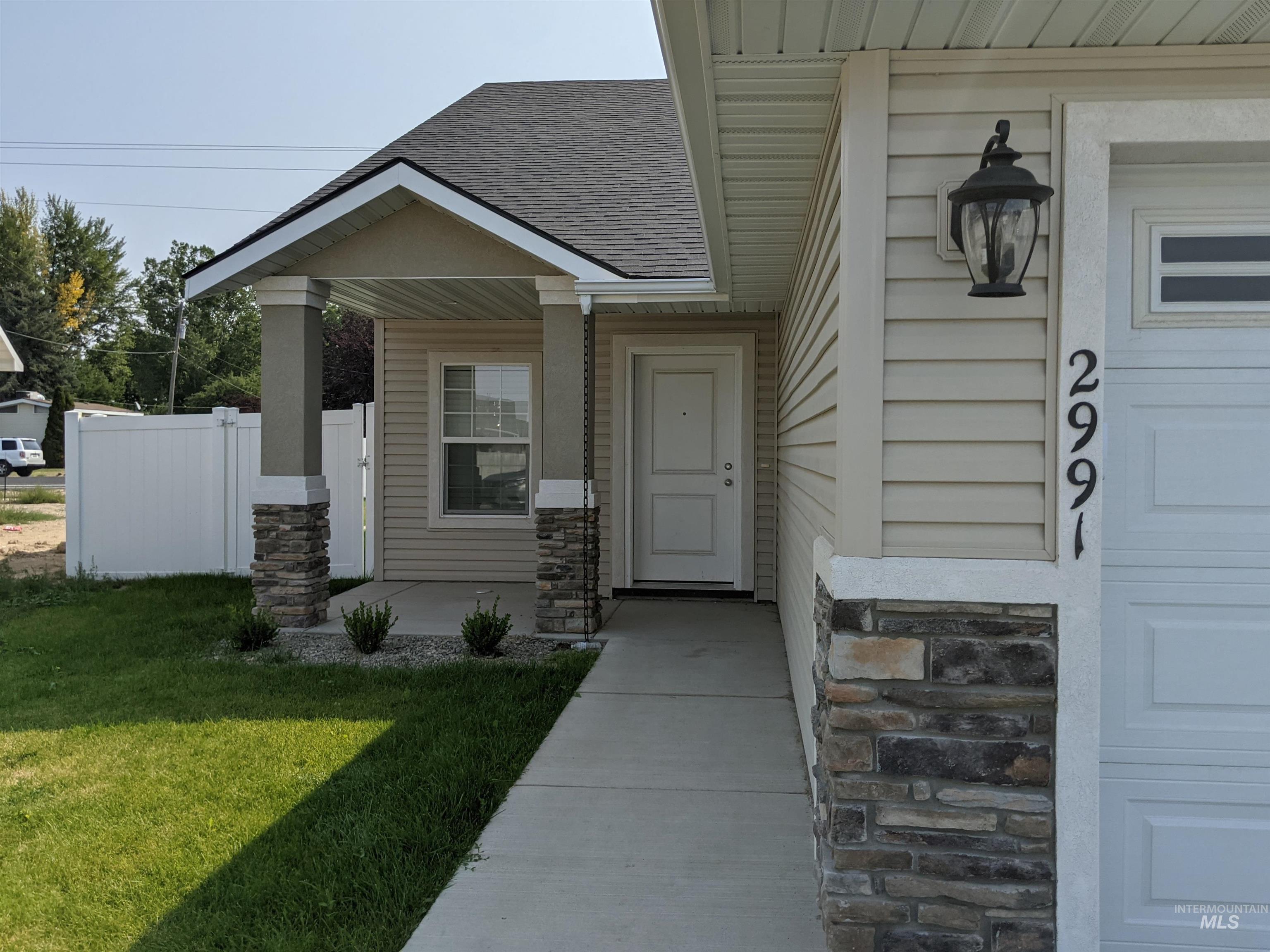 Property entrance featuring covered porch, a shingled roof, and stone siding
