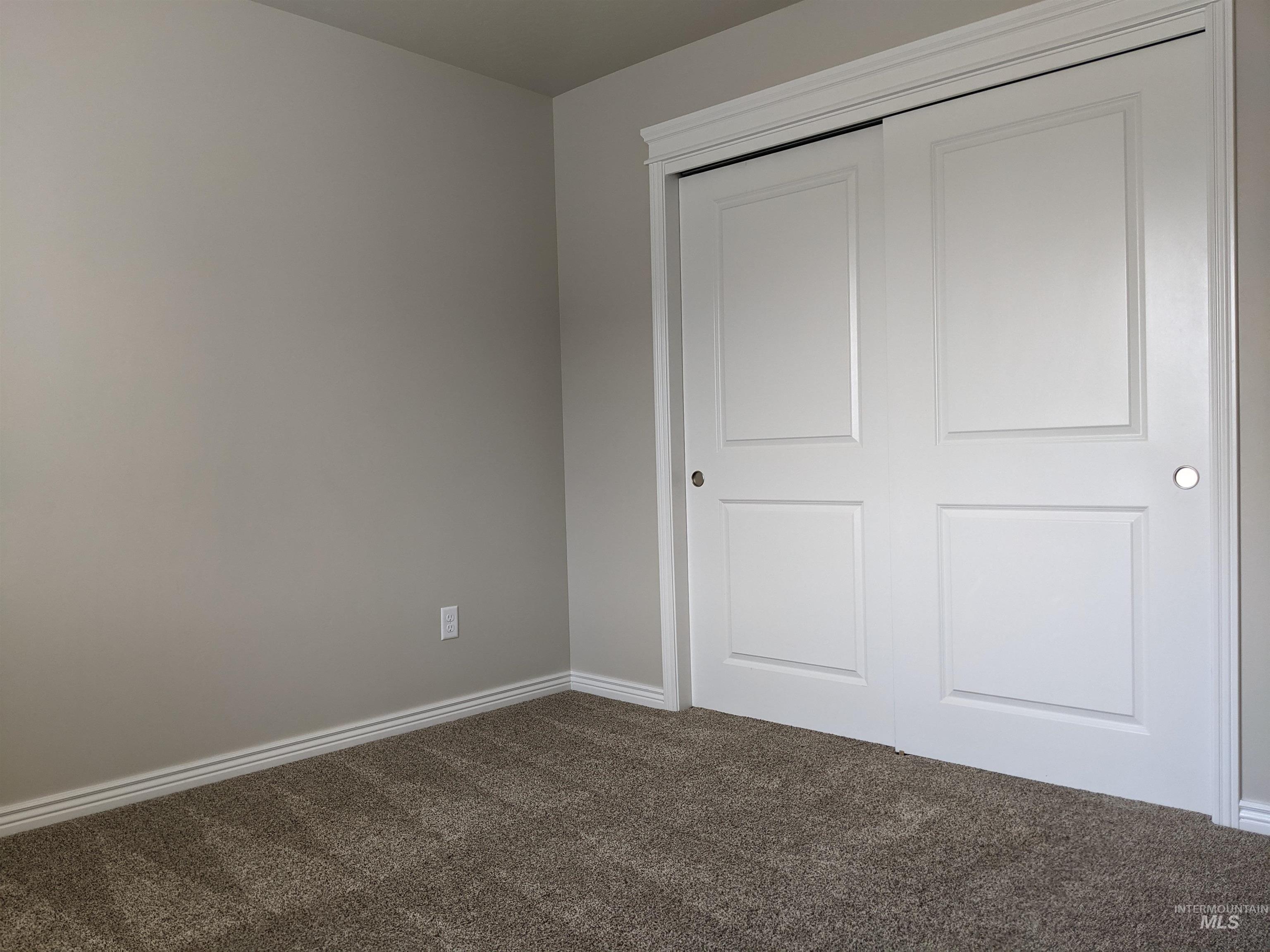 Unfurnished bedroom with dark colored carpet and a closet
