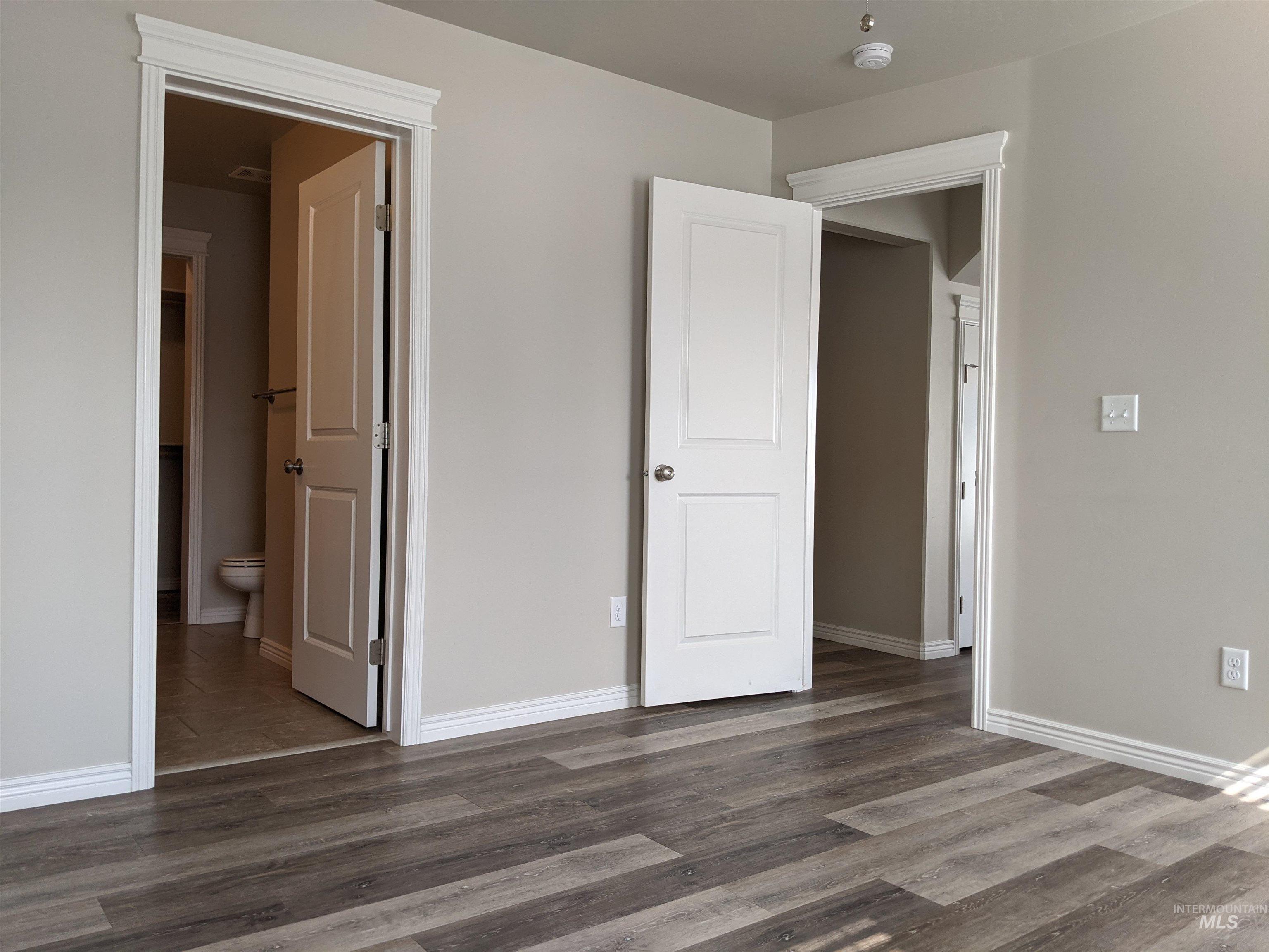 Unfurnished bedroom with dark wood finished floors and ensuite bathroom