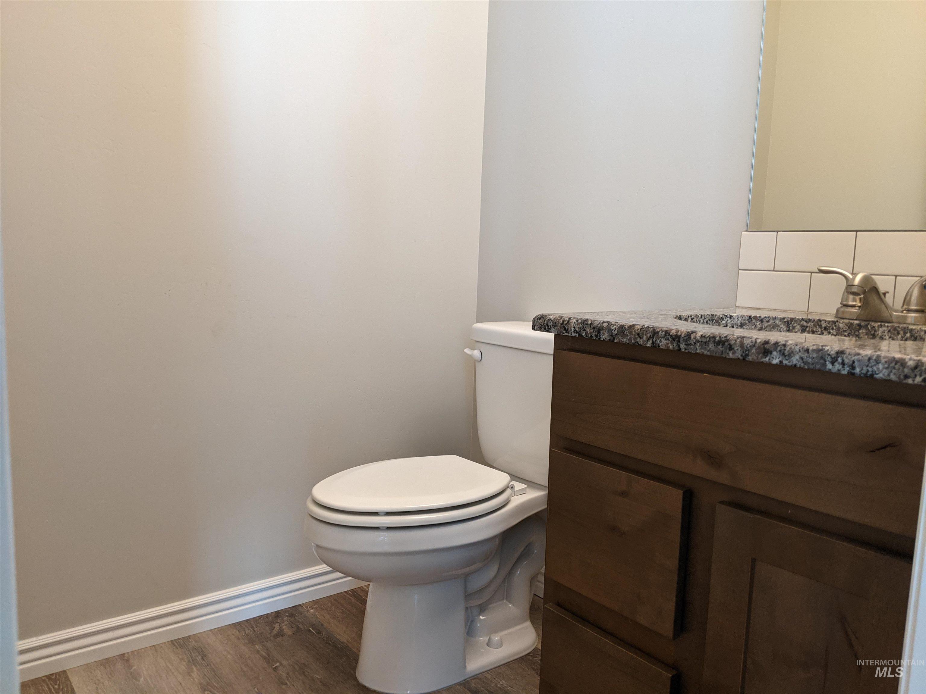Half bath with vanity and dark wood-type flooring