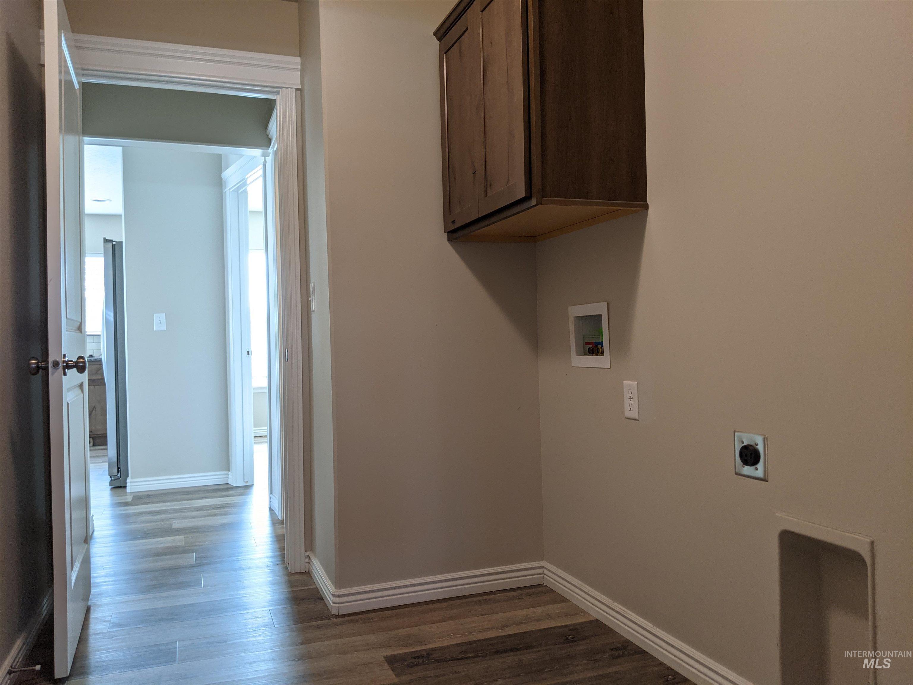Laundry area featuring dark wood-style flooring, washer hookup, hookup for an electric dryer, and cabinet space