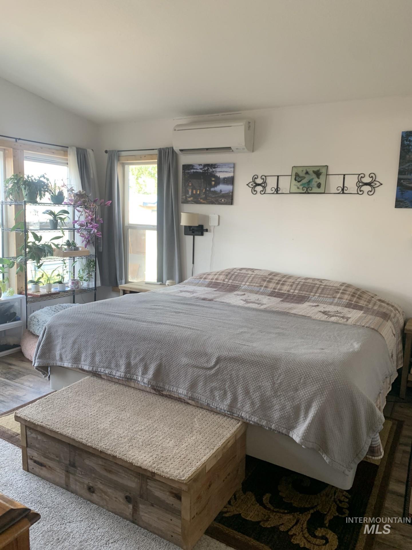 Bedroom featuring a wall unit AC and wood finished floors