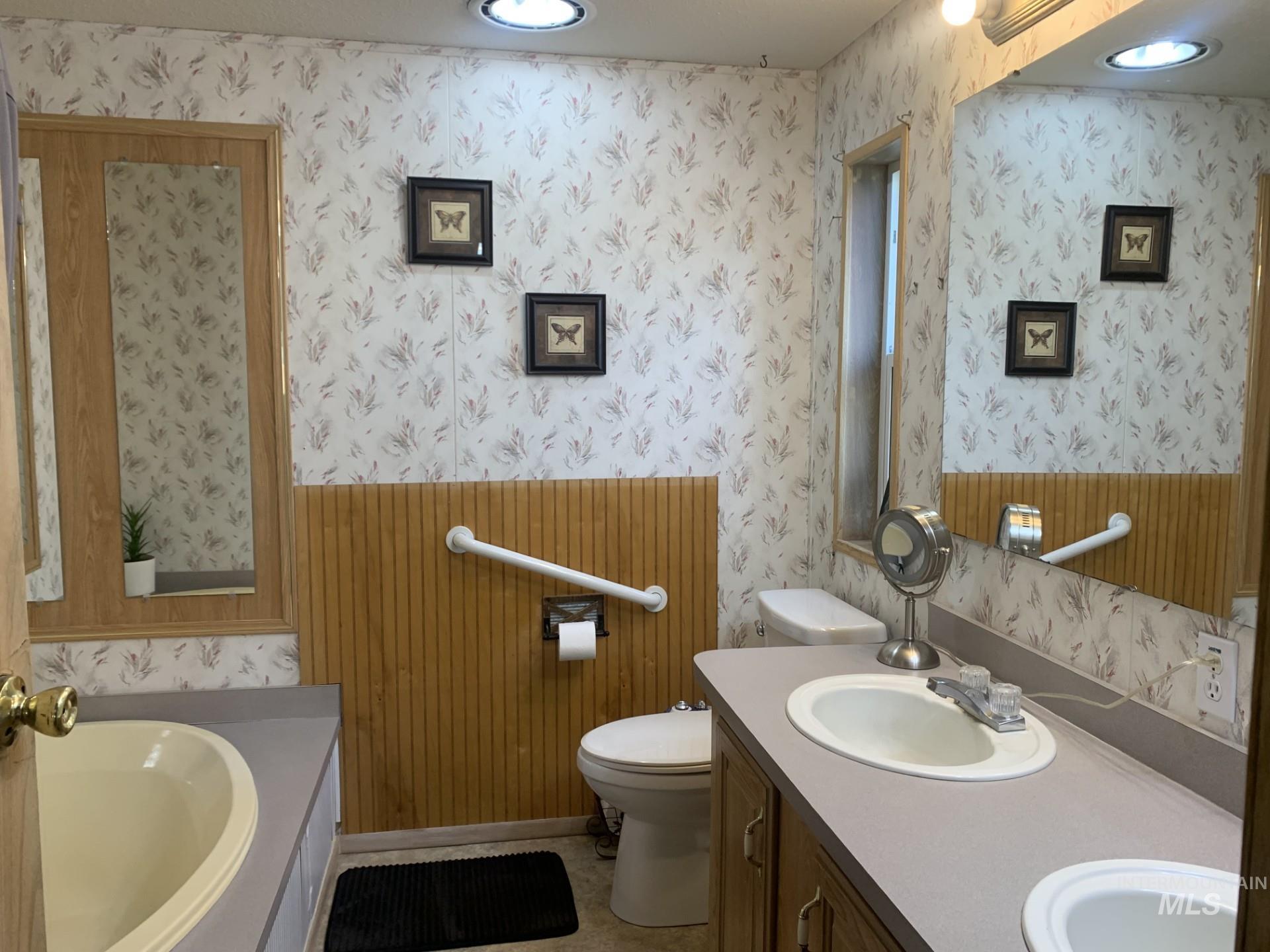 Bathroom featuring double vanity, wallpapered walls, a garden tub, and recessed lighting
