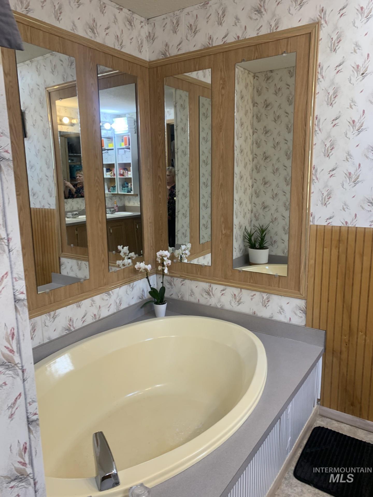 Full bath featuring wallpapered walls, a garden tub, wooden walls, and a wainscoted wall