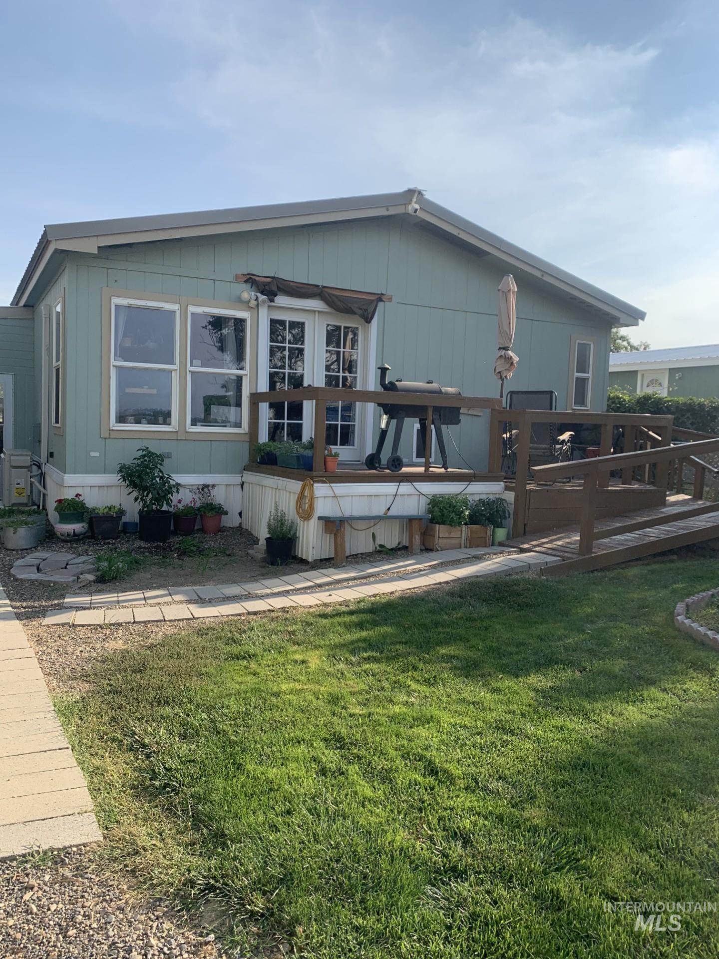 Back of house with a deck and a lawn