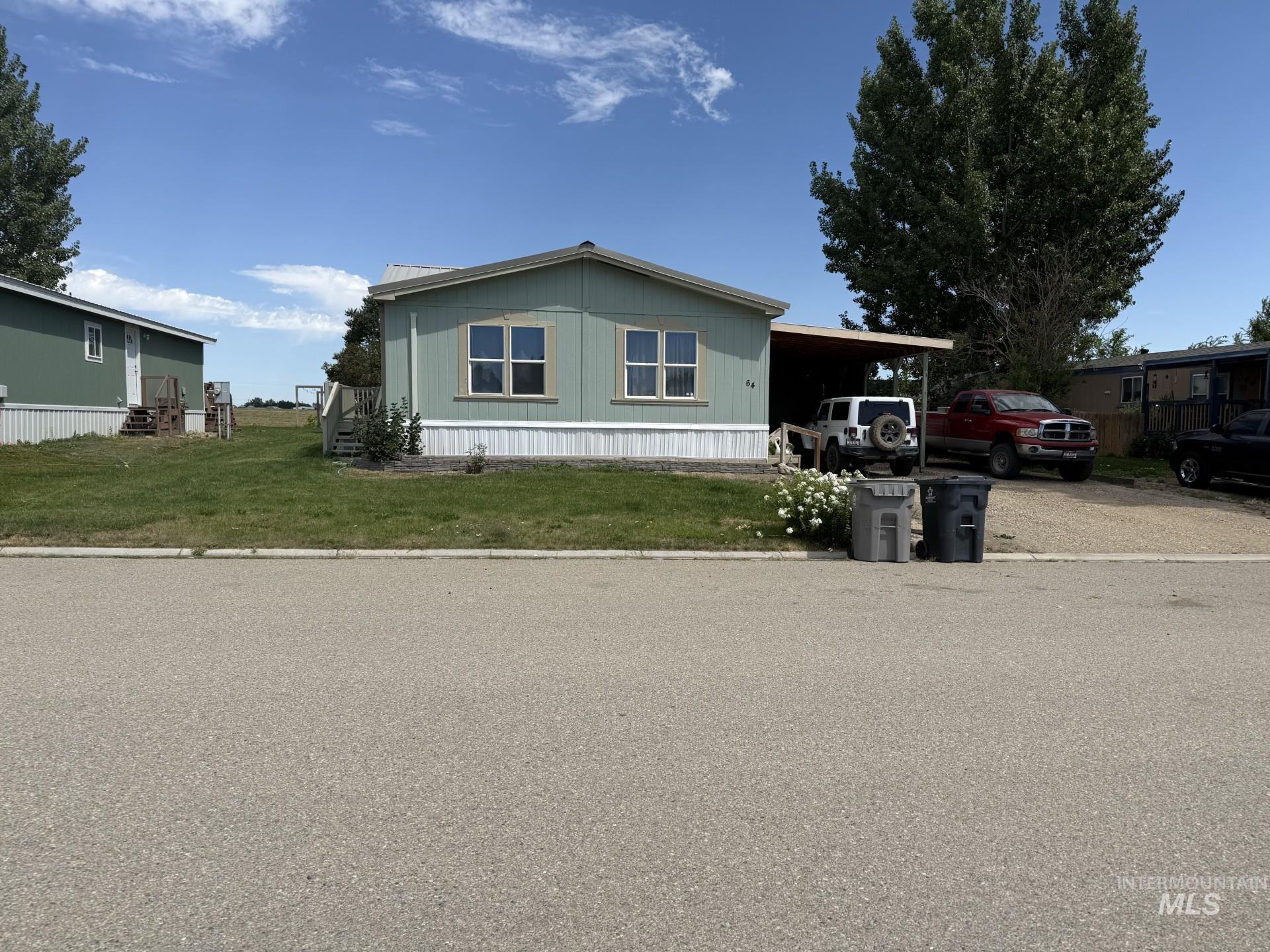 Manufactured / mobile home with a front yard, an attached carport, and driveway