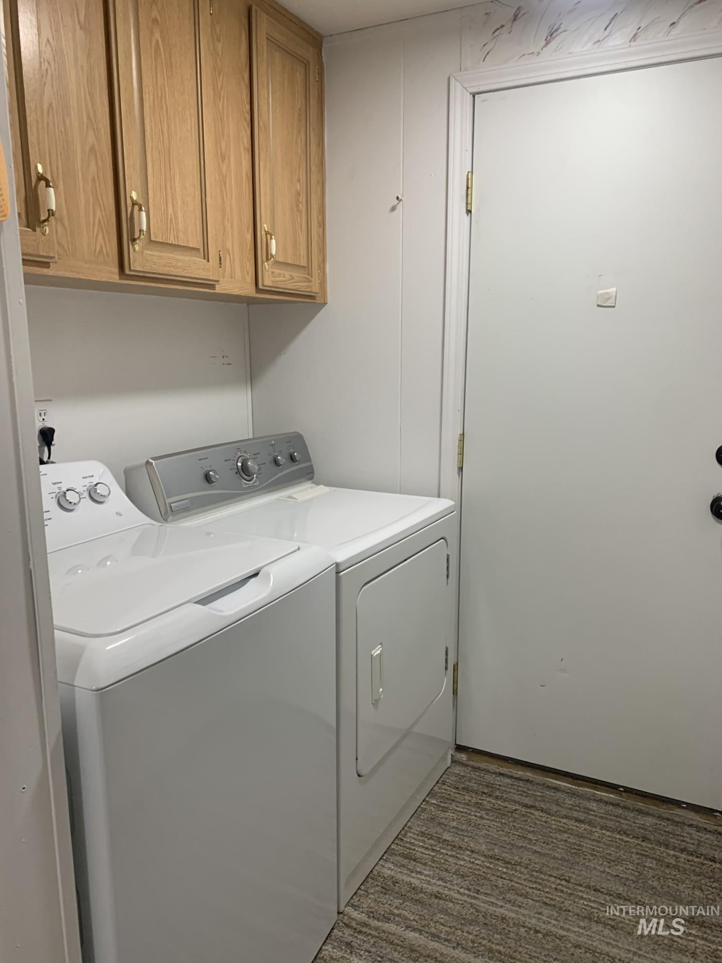 Laundry area with washing machine and dryer, cabinet space, and dark carpet