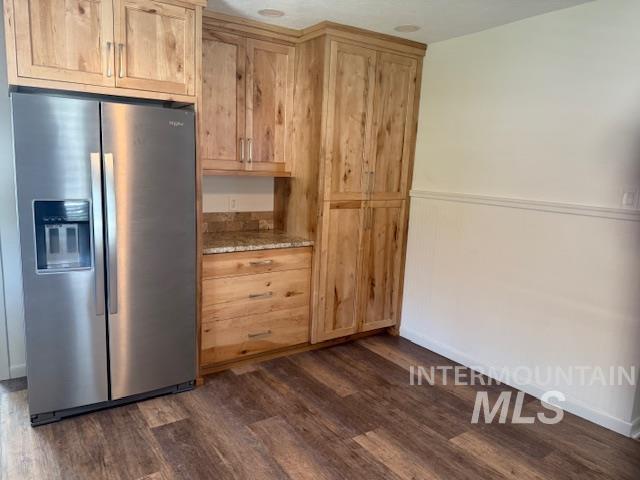 Kitchen featuring stainless steel fridge with ice dispenser, dark wood-style flooring, light brown cabinetry, and light stone counters