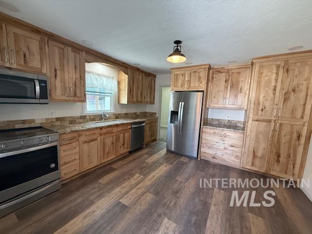 Kitchen featuring stainless steel appliances, dark wood-style flooring, light brown cabinetry, and light stone countertops