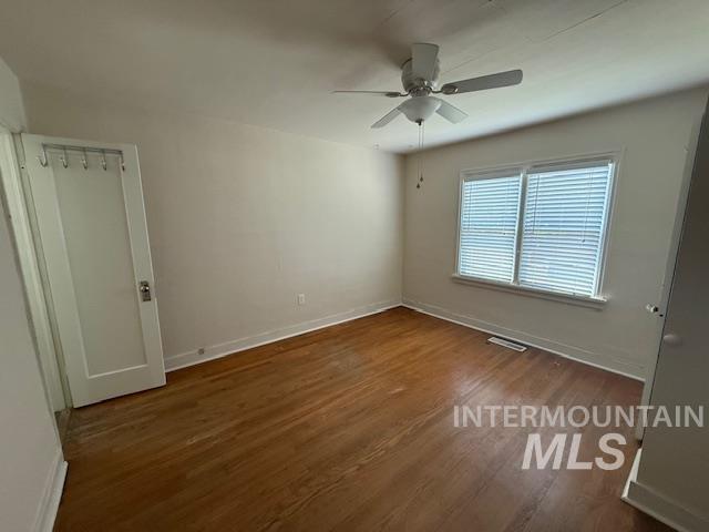 Unfurnished bedroom featuring dark wood-type flooring and ceiling fan