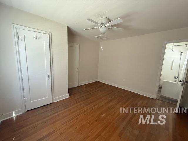 Unfurnished bedroom featuring dark wood-style floors, a ceiling fan, and a closet