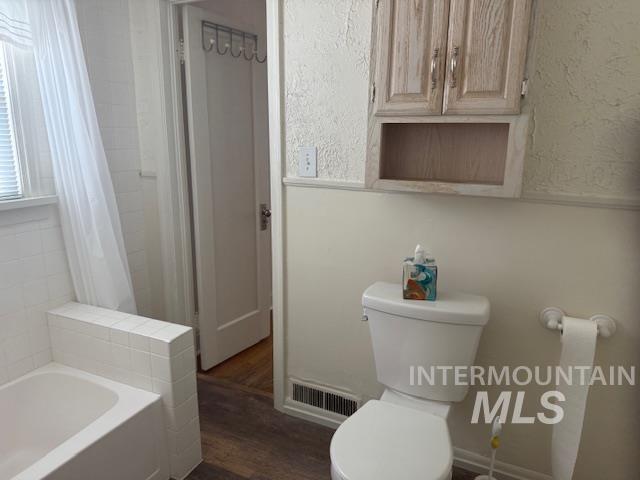 Full bath featuring dark wood-type flooring and shower / tub combo