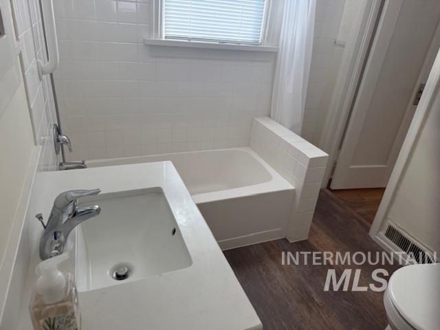 Full bath with vanity, dark wood-type flooring, and shower / tub combo