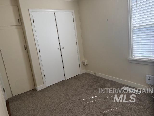 Unfurnished bedroom with carpet flooring, a closet, and multiple windows