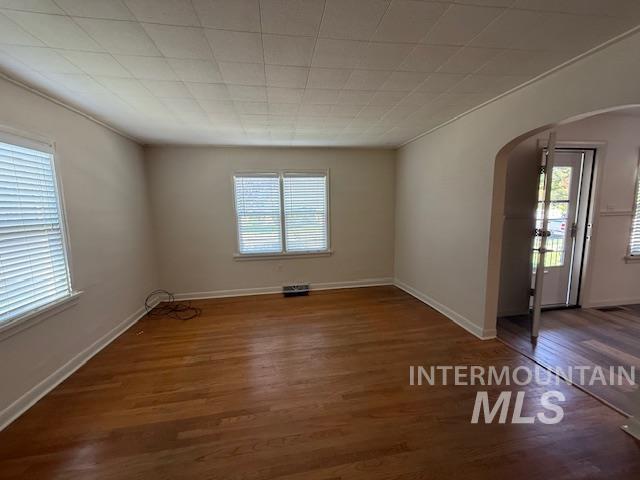 Unfurnished room with arched walkways and wood finished floors