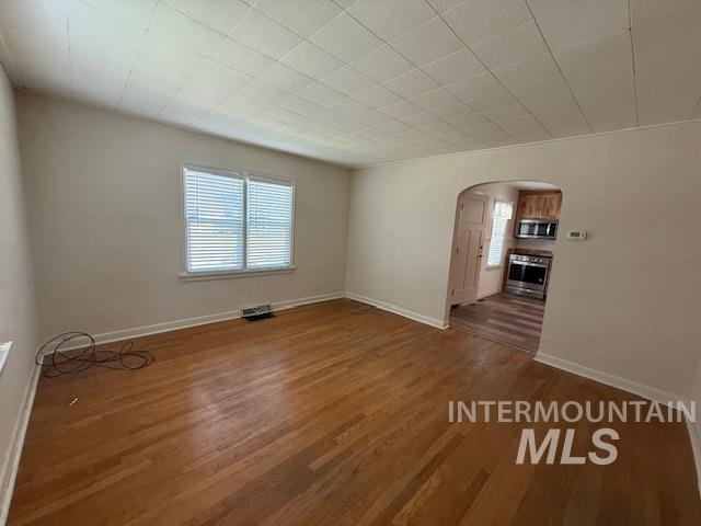 Spare room featuring arched walkways, wood finished floors, and healthy amount of natural light