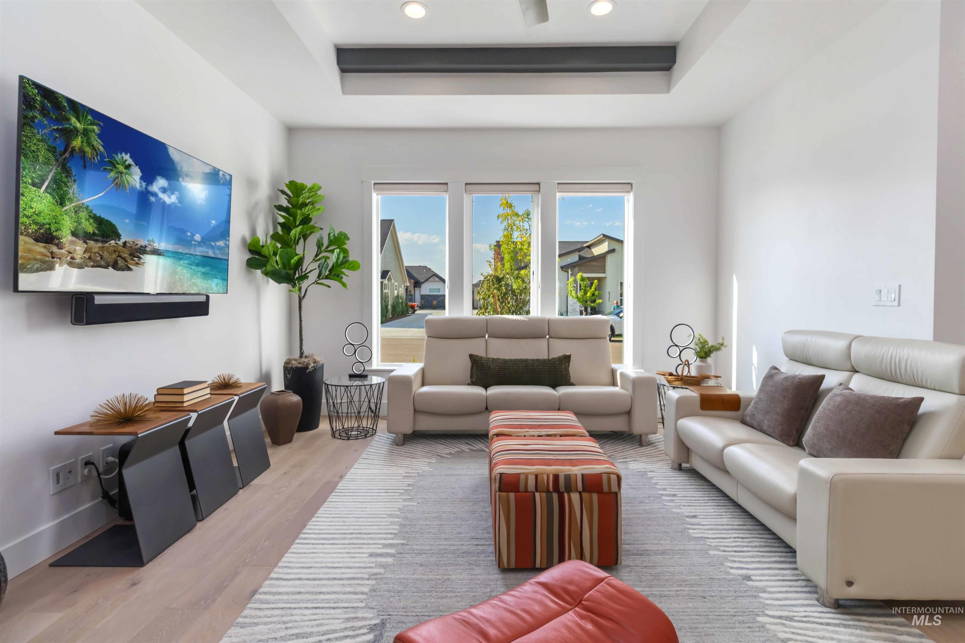 Living area with wood finished floors, a tray ceiling, and recessed lighting