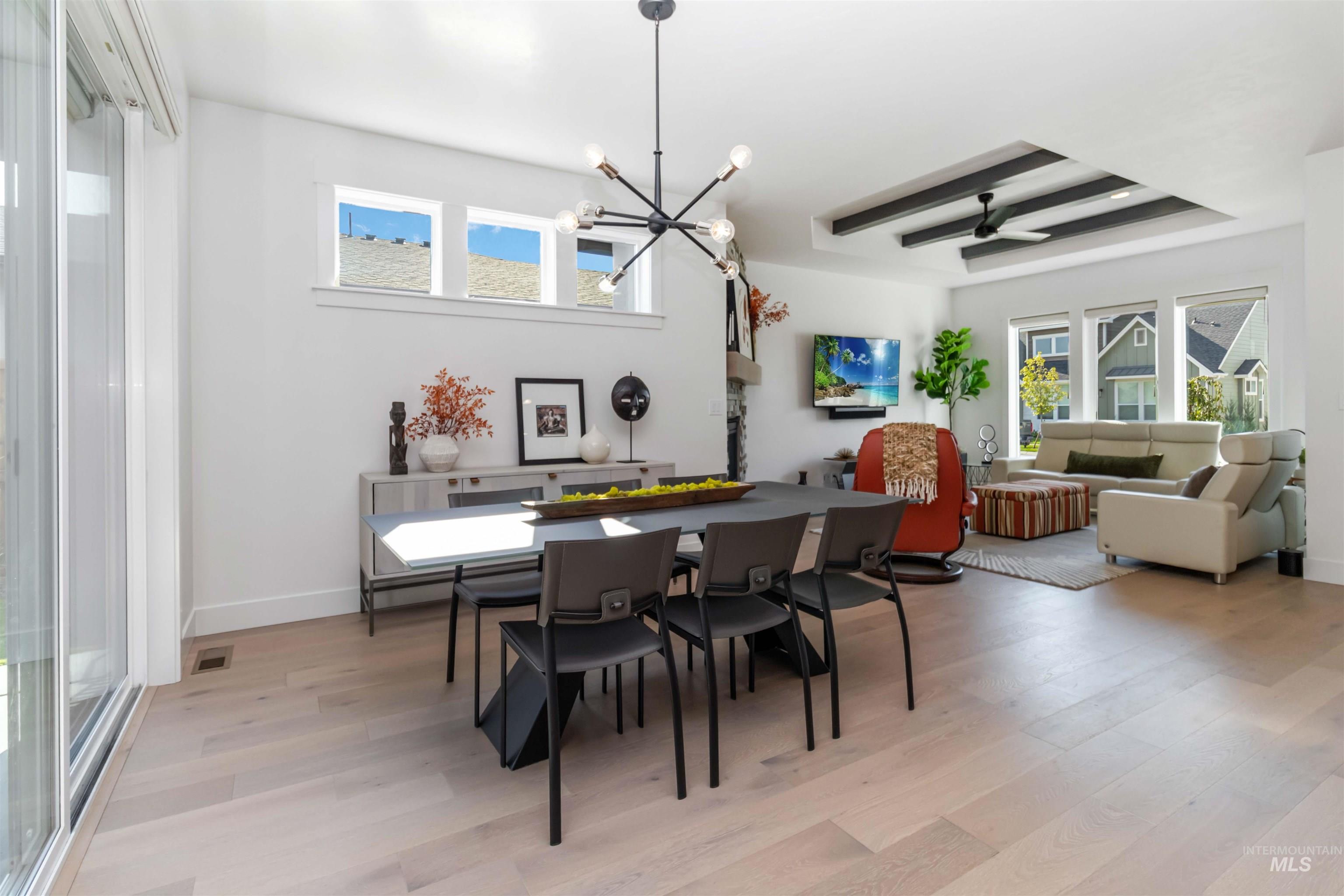 Dining room with plenty of natural light, light wood-style floors, a chandelier, and ceiling fan