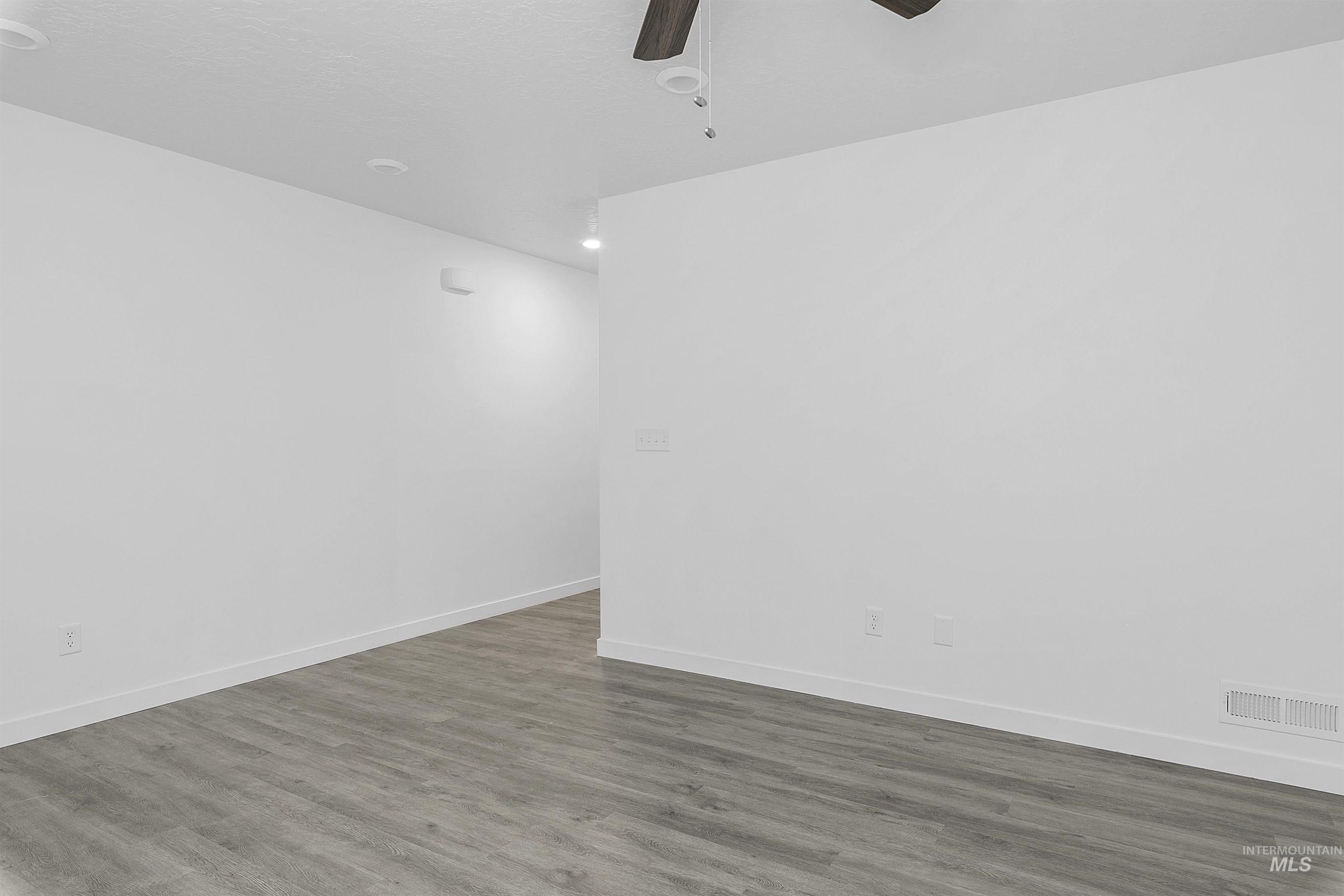 Empty room featuring dark wood-type flooring and ceiling fan