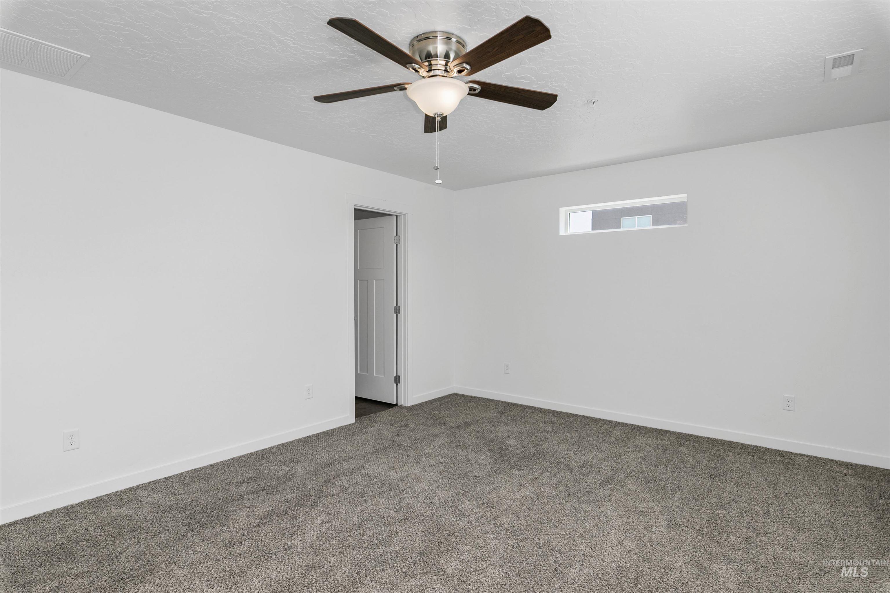 Spare room featuring carpet flooring, a textured ceiling, and ceiling fan
