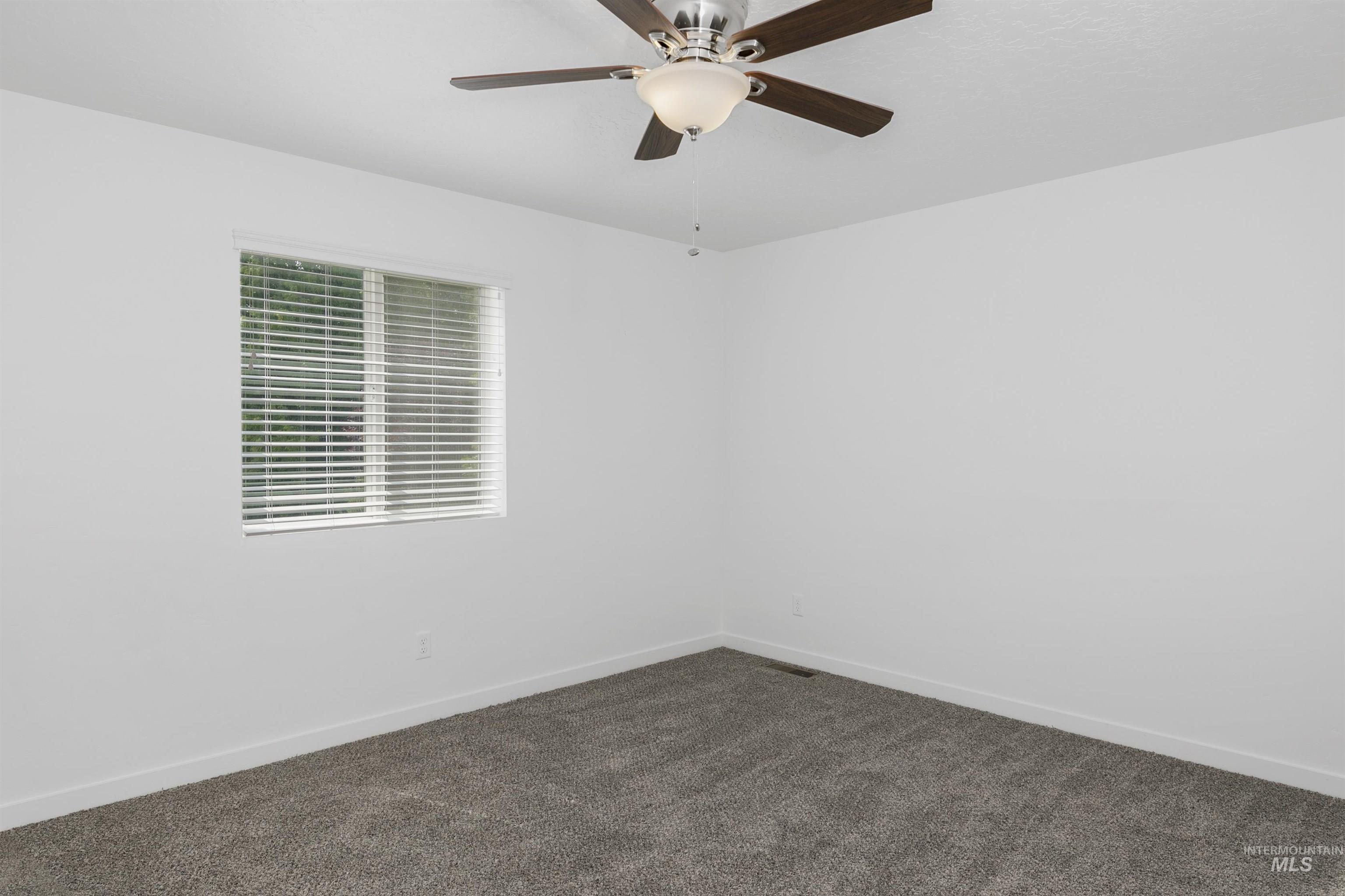 Empty room with dark carpet and ceiling fan