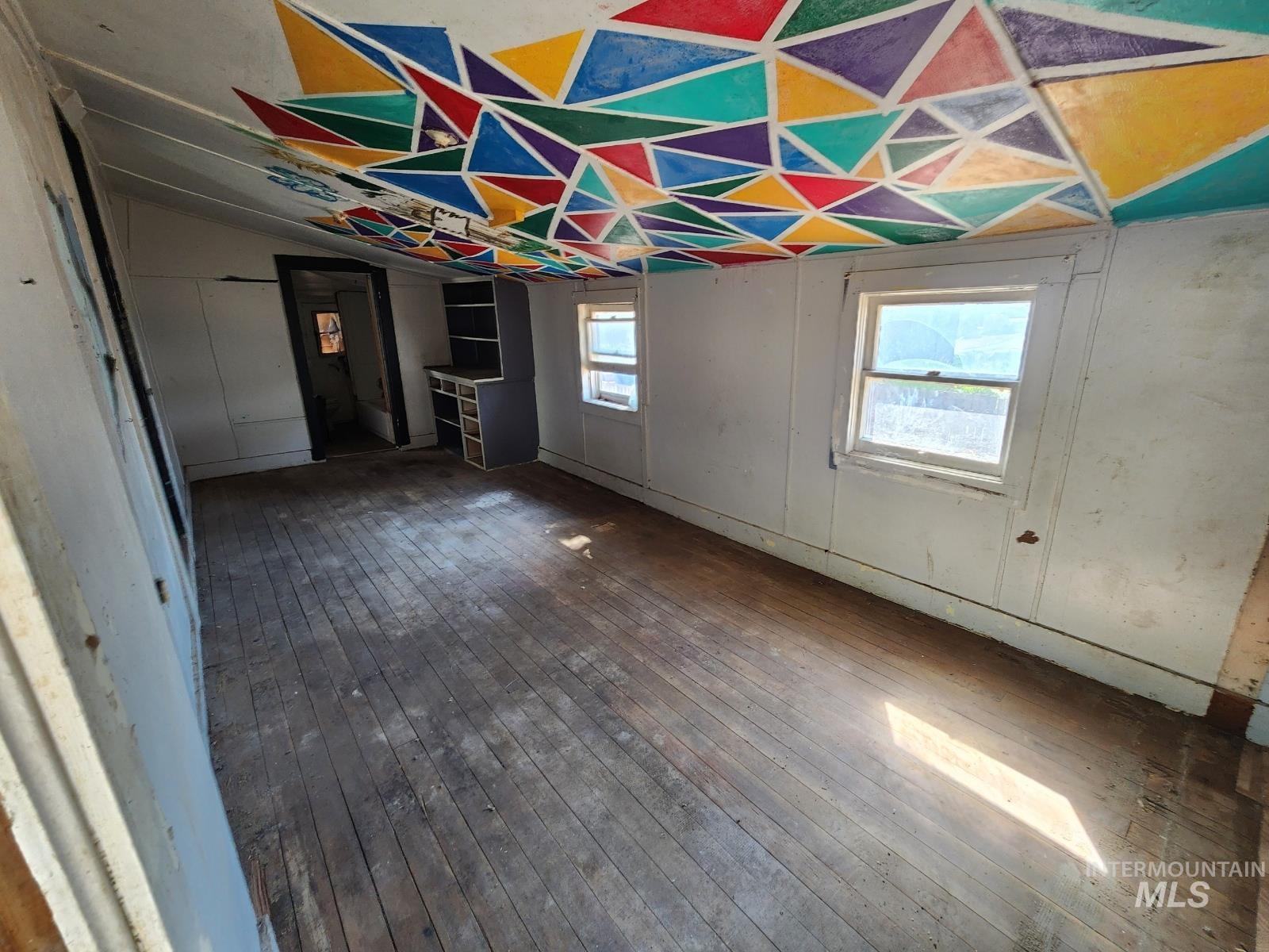 Unfurnished dining area with wood-type flooring and vaulted ceiling