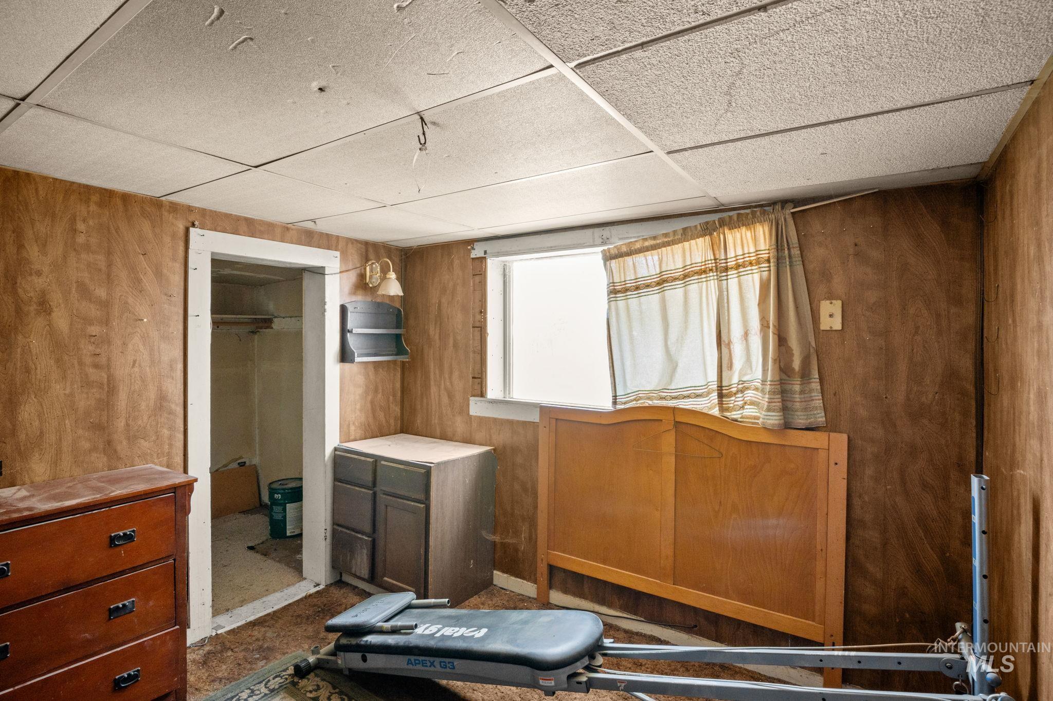 Bedroom featuring wood walls and a drop ceiling