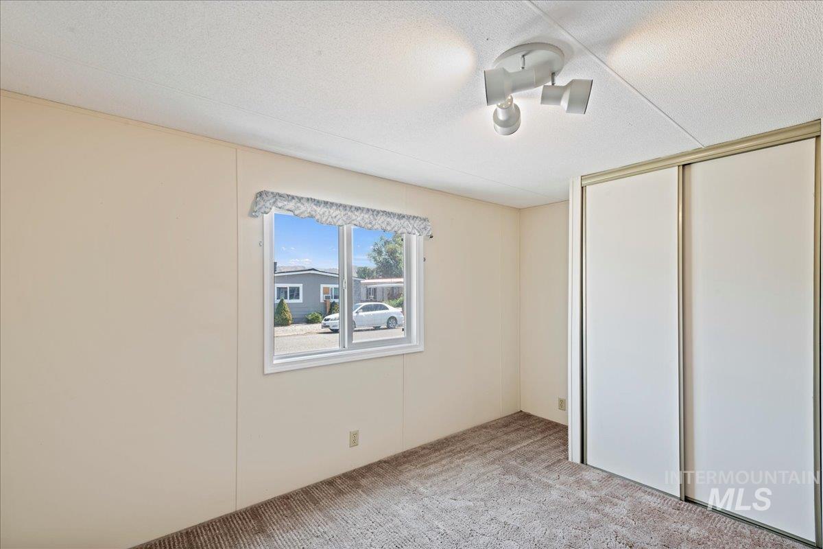 Unfurnished bedroom with light colored carpet, a closet, and a textured ceiling