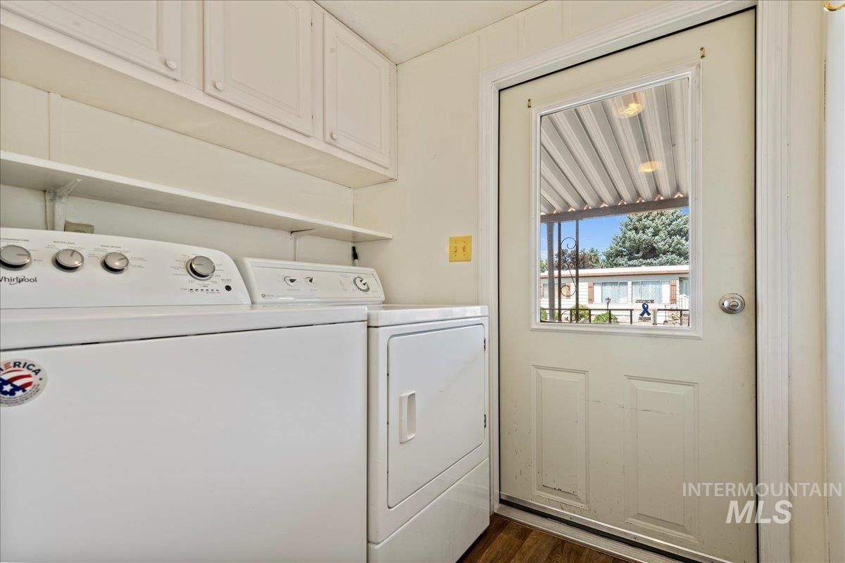 Washroom featuring washing machine and dryer, dark wood-type flooring, and cabinet space