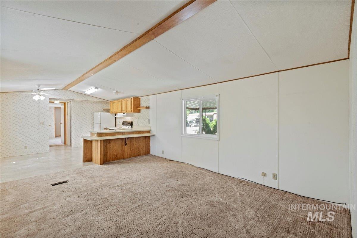 Kitchen with light colored carpet, light countertops, wallpapered walls, a peninsula, and freestanding refrigerator