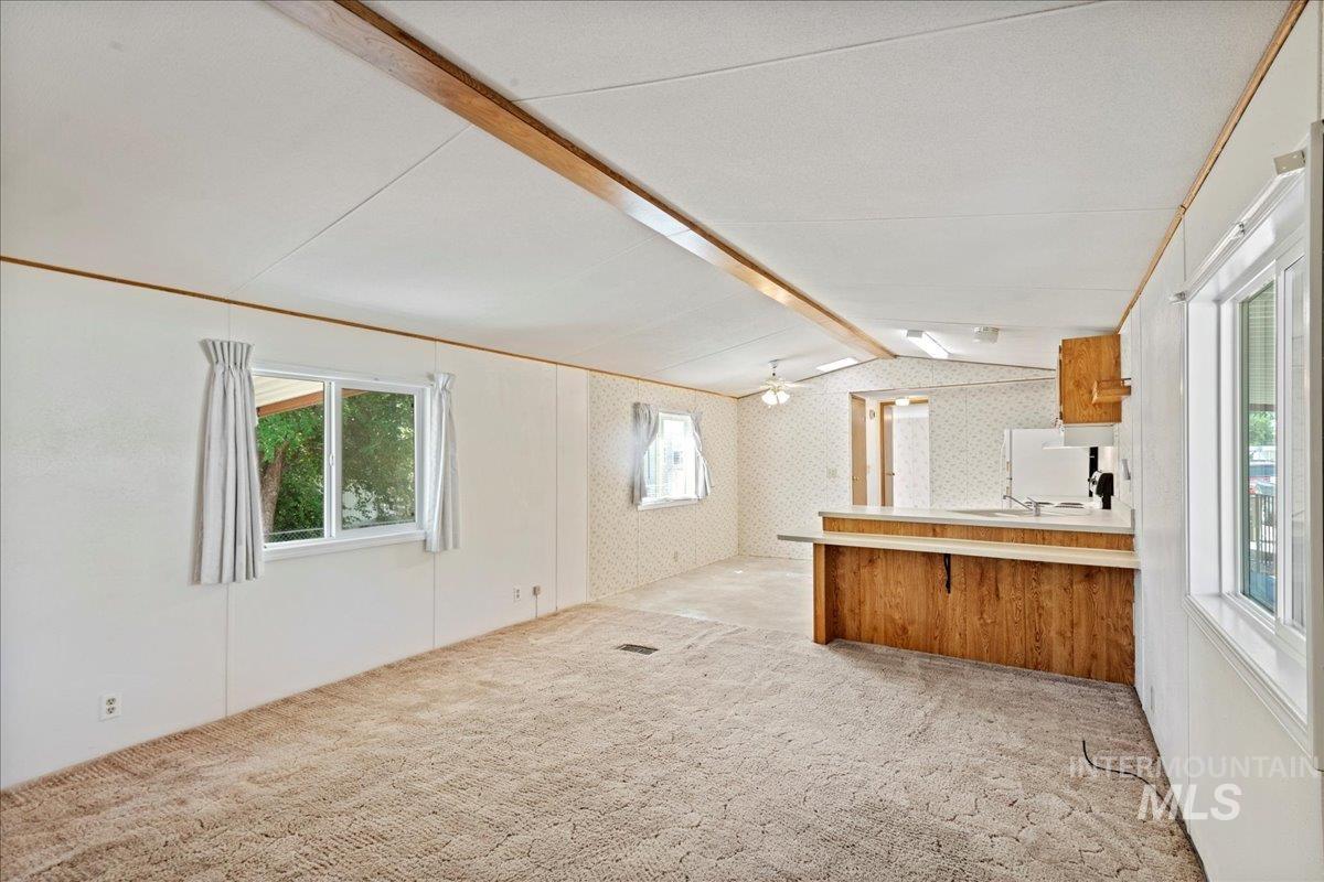 Kitchen with light carpet, light countertops, brown cabinets, a peninsula, and a breakfast bar