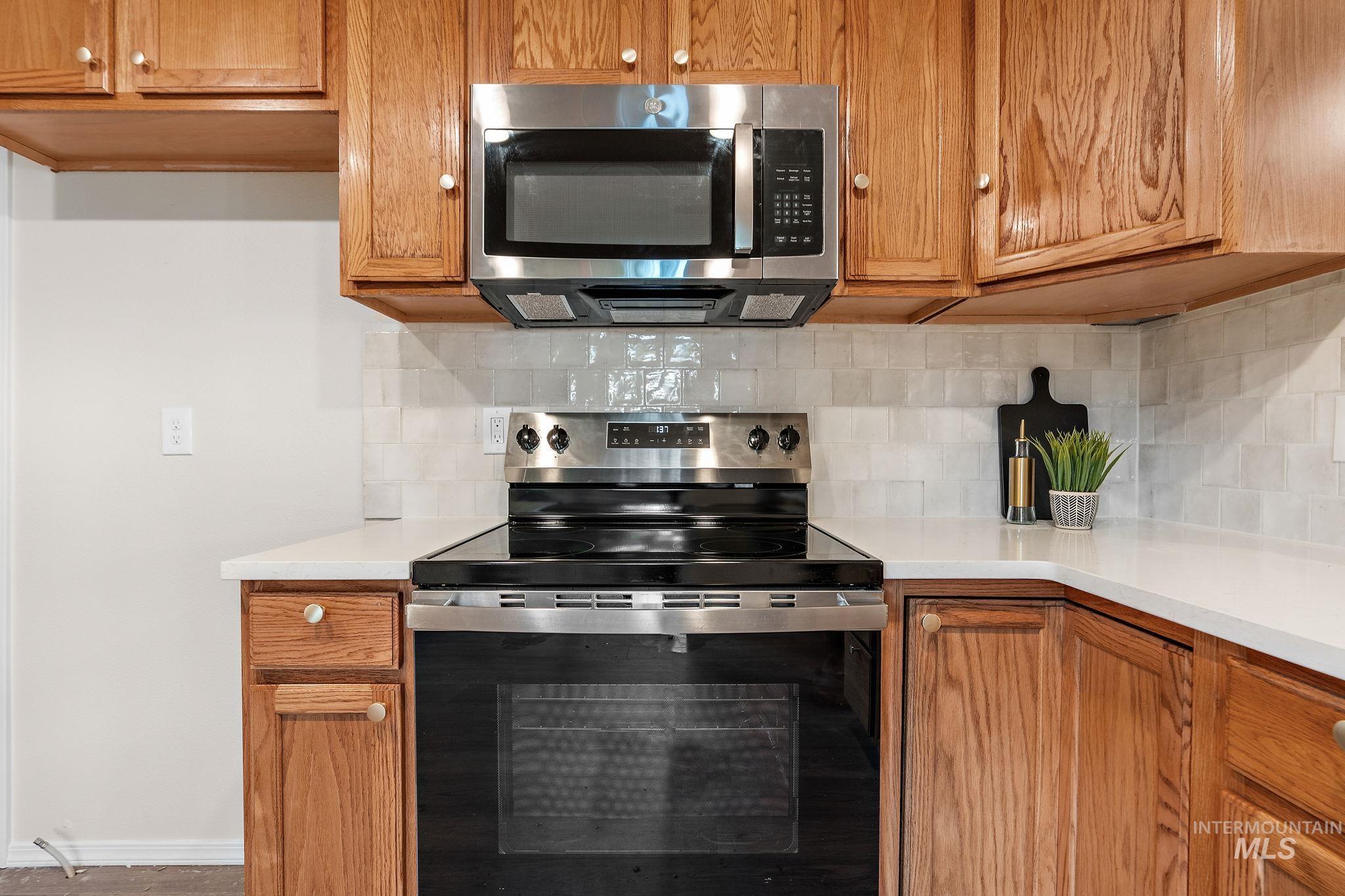Kitchen featuring stainless steel appliances, brown cabinetry, and backsplash