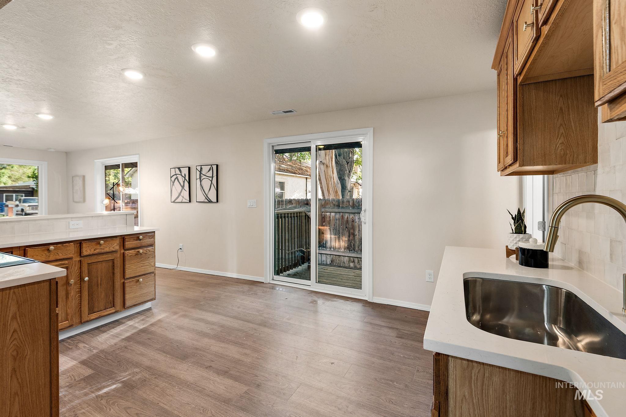Kitchen featuring brown cabinets, wood finished floors, recessed lighting, a textured ceiling, and backsplash