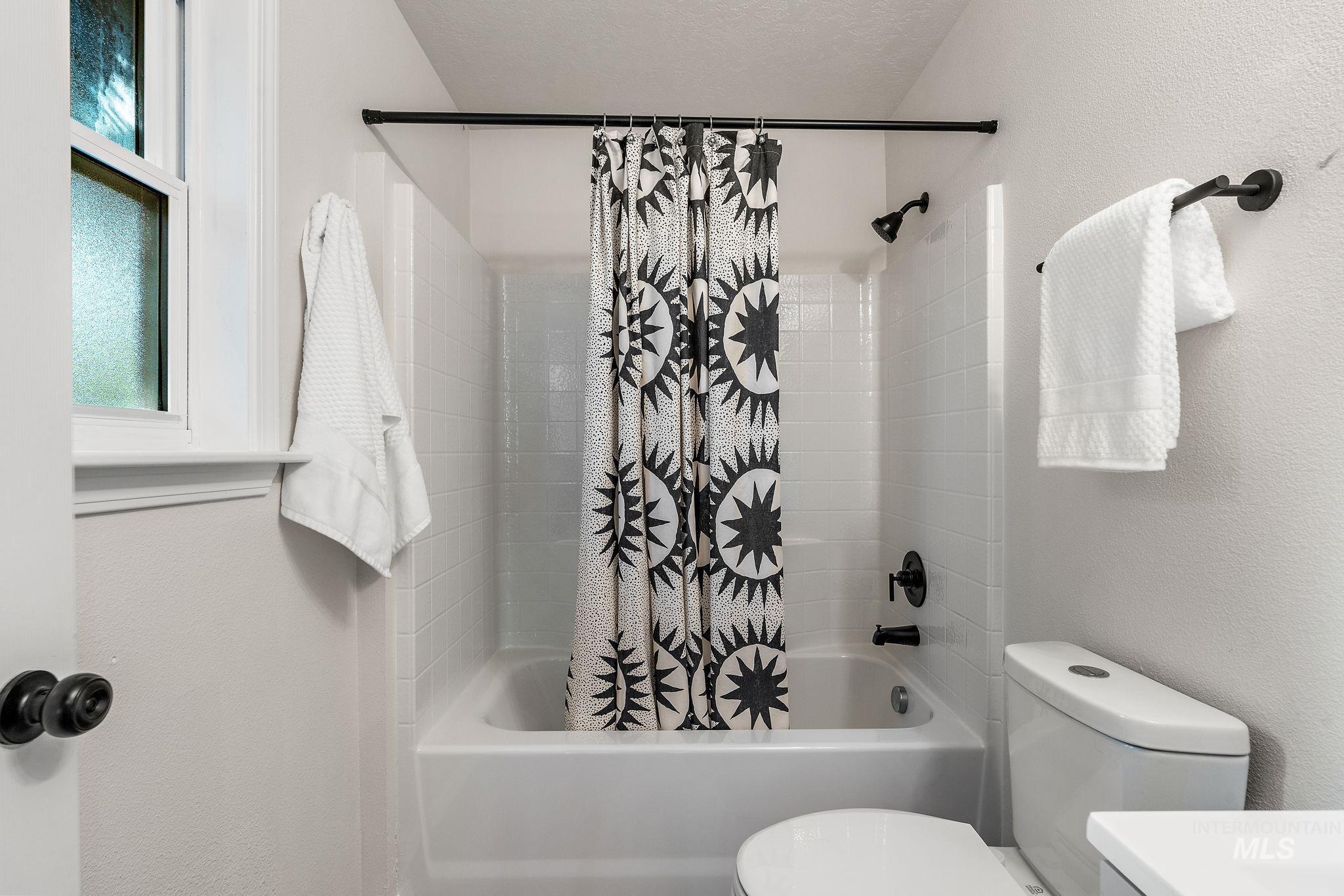 Full bathroom with shower / bath combination with curtain, a textured wall, vanity, and a textured ceiling