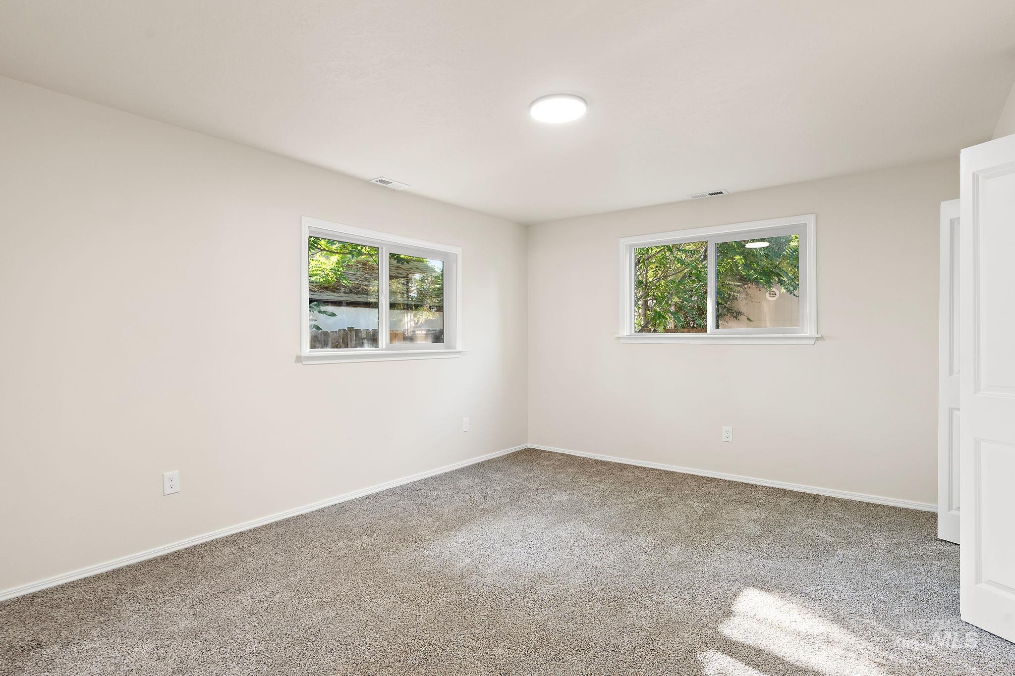 Unfurnished bedroom with light carpet and baseboards
